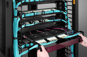 Technician terminating orange fiber optic cables at a patch panel